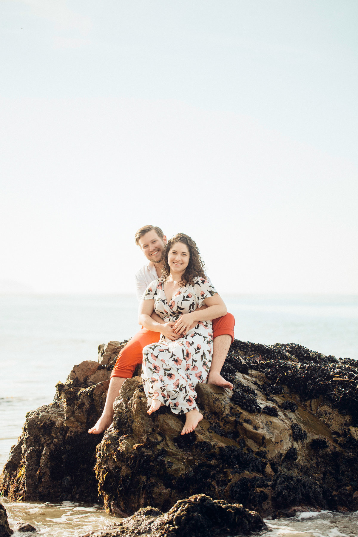 Engagement Photograph Of  Man Hugging a Woman From The Back While Seated On a Rock Los Angeles