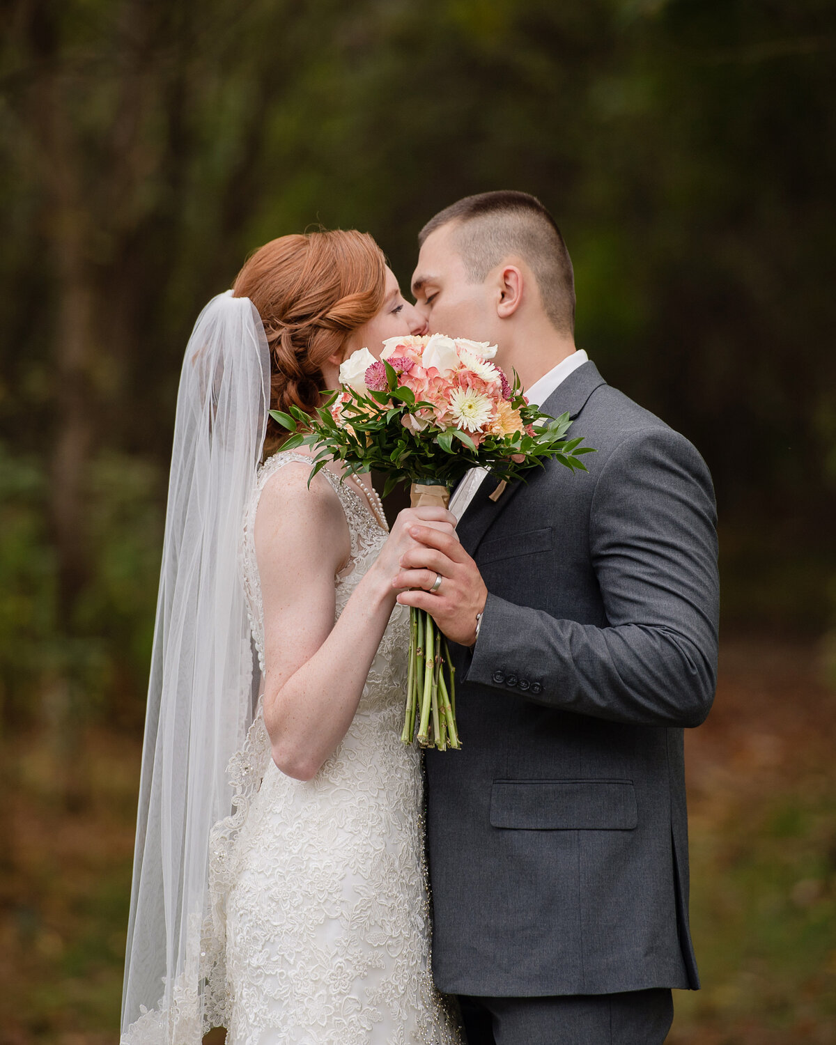 wedding couple kiss behind bouquet