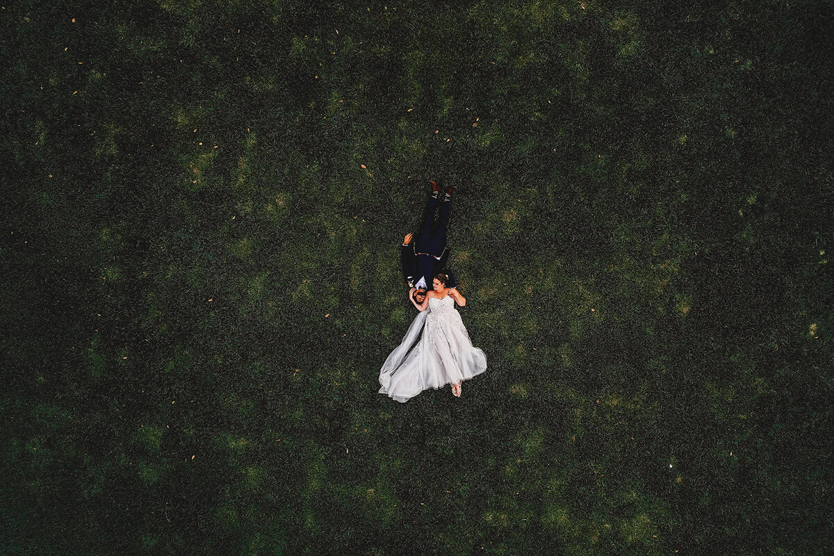 Baltimore wedding photographers captures unique wedding photography with bride and groom laying together in a large green field photographed in a Birdseye view perspective