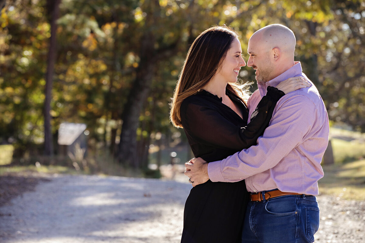 Loving couple sharing a quiet moment on gravel path surrounded by golden leaves at Anne Springs Close Greenway Charlotte NC