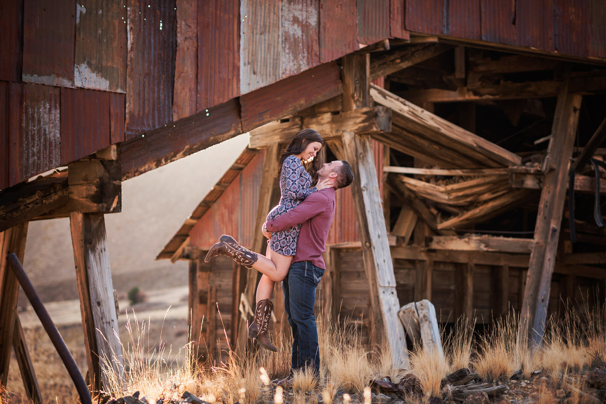 Man lifts and spins woman in rustic setting