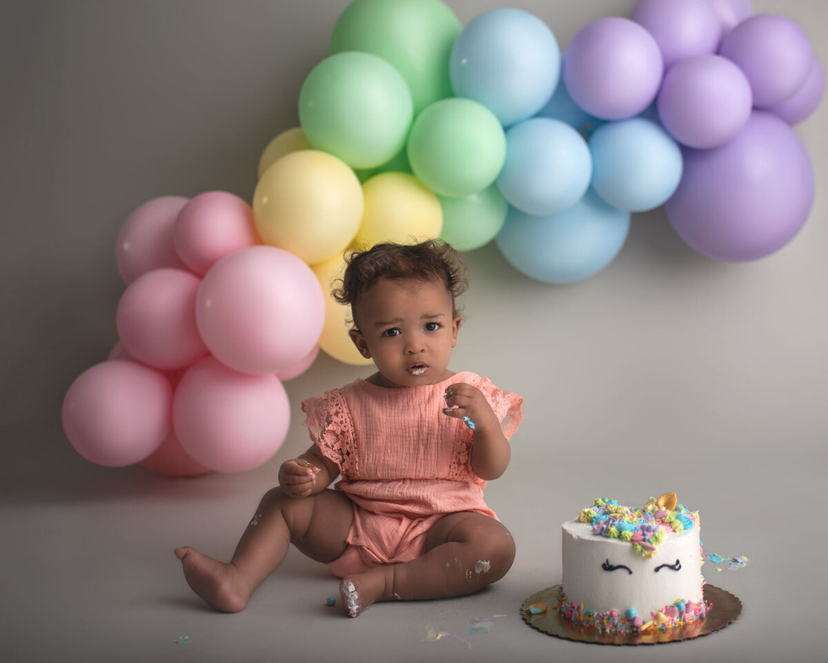 baby looking at camera next to unicorn cake by st. louis cake smash photographer