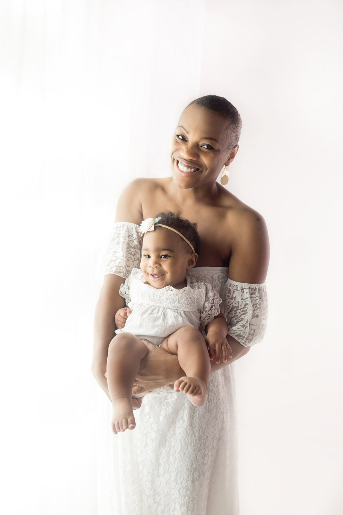 Mom wearing white gown, holding baby during mommy and me photoshoot in Brentwood Tennessee photography studio