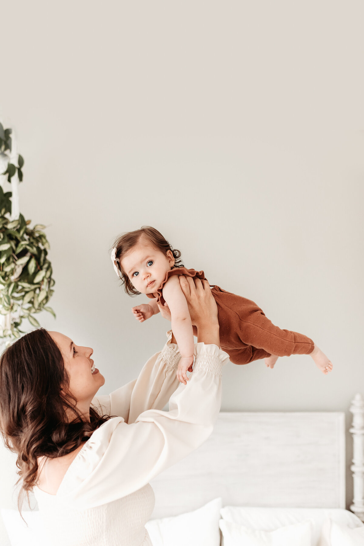 mom lifting baby girl into the air