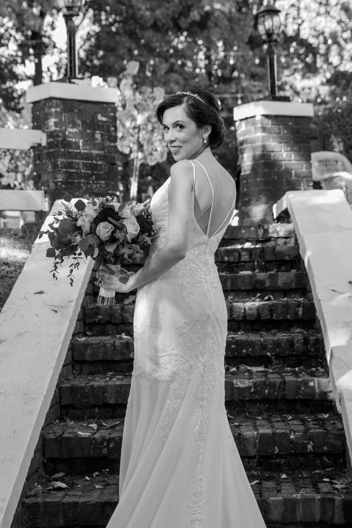 black and white photo of a bride looking over her shoulder on stone steps at Briarcliff Manor Wedding Photographer Milestone Images