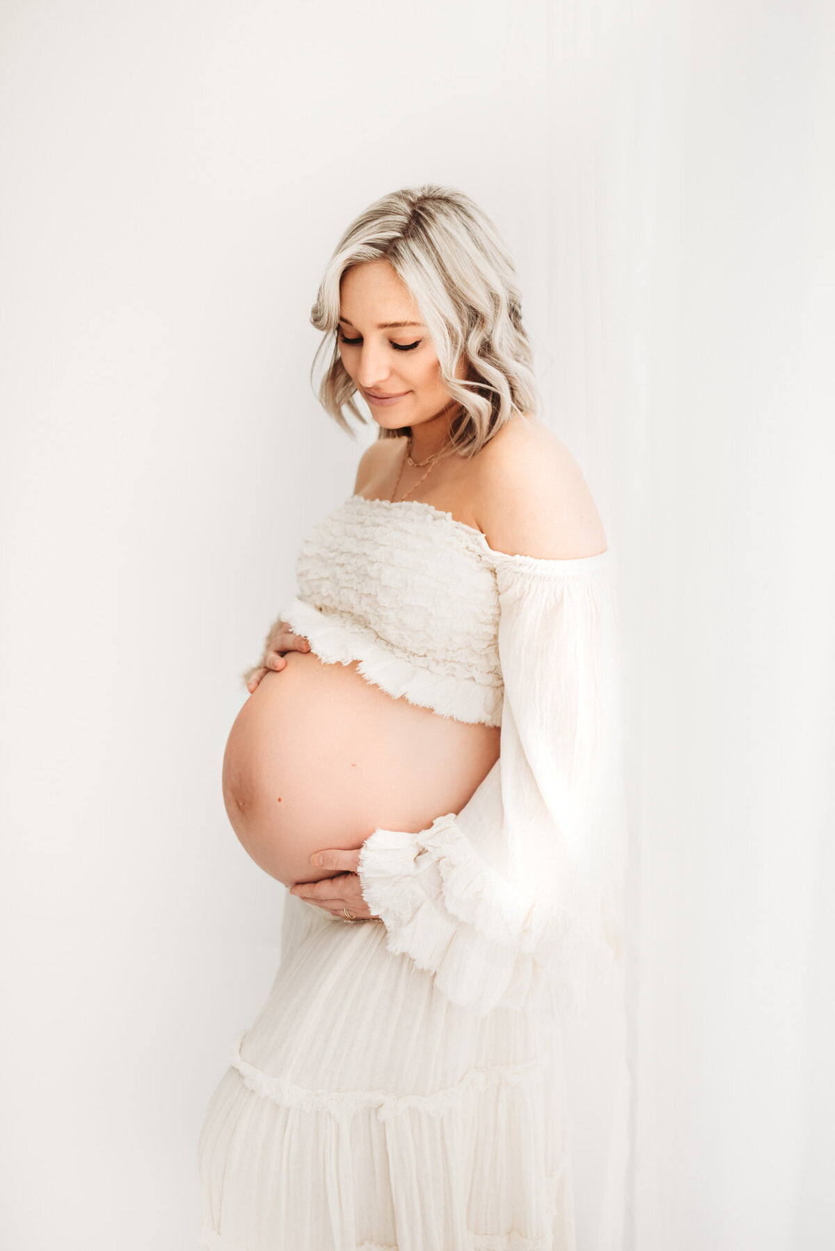 denver maternity photographer with pregnant woman in white studio room