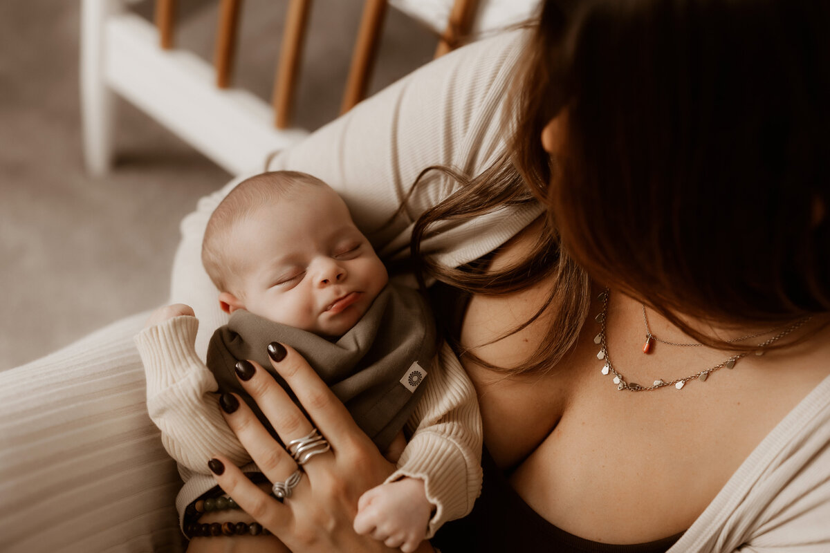 new baby boy sleeps in moms arms in nursery