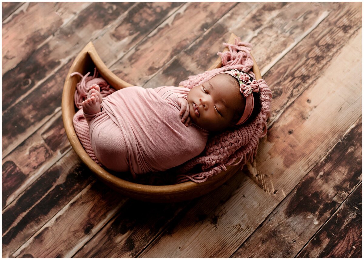 A newborn baby peacefully sleeping on a beautifully decorated moon prop bed during a newborn photography session.