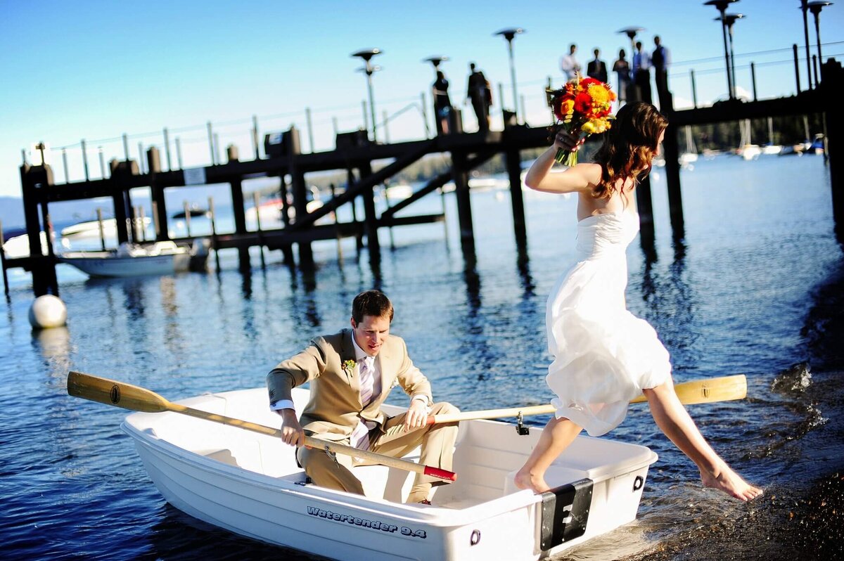 Bride jumping off dingy while her groom is paddling in Lake Tahoe at west shore cafe