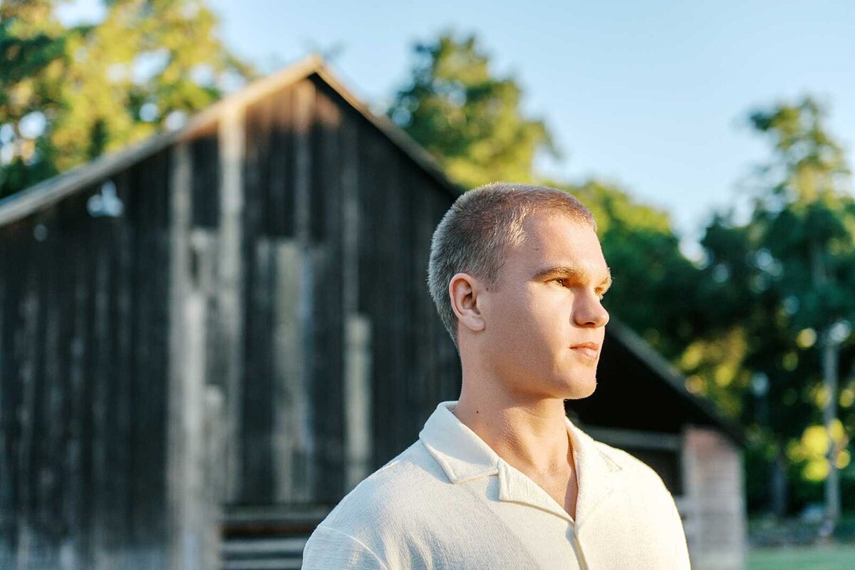Direct sun senior guy picture with a barn in the background