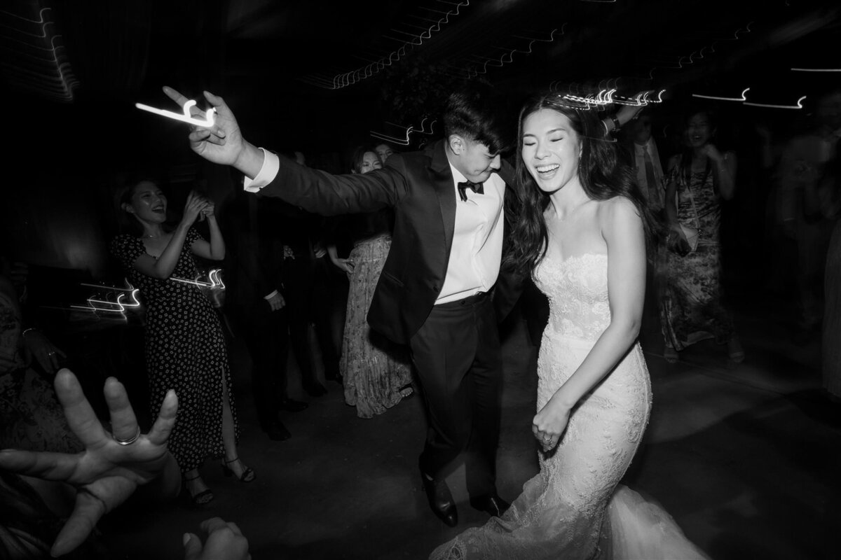 Black and white photo of bride and groom dancing at wedding reception.