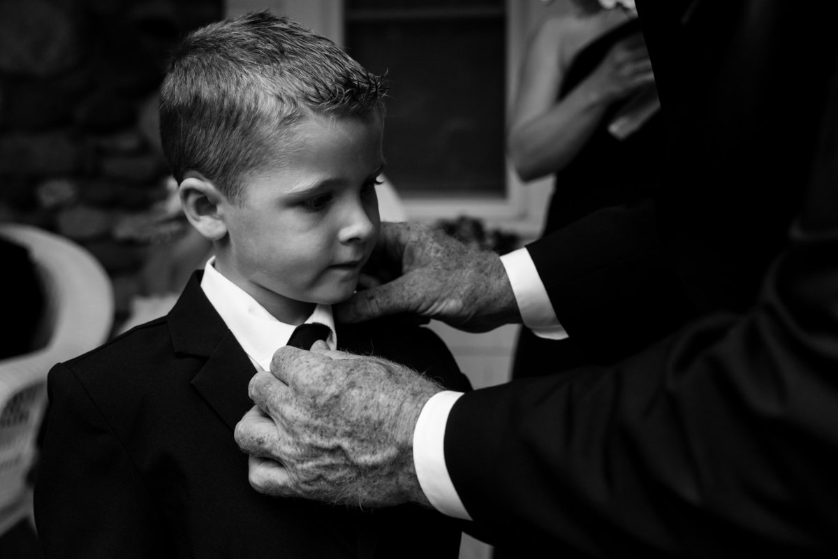 The father of the bride adjusts his grandson's tie at the Pot & Kettle Club wedding  in Hulls Cove Maine