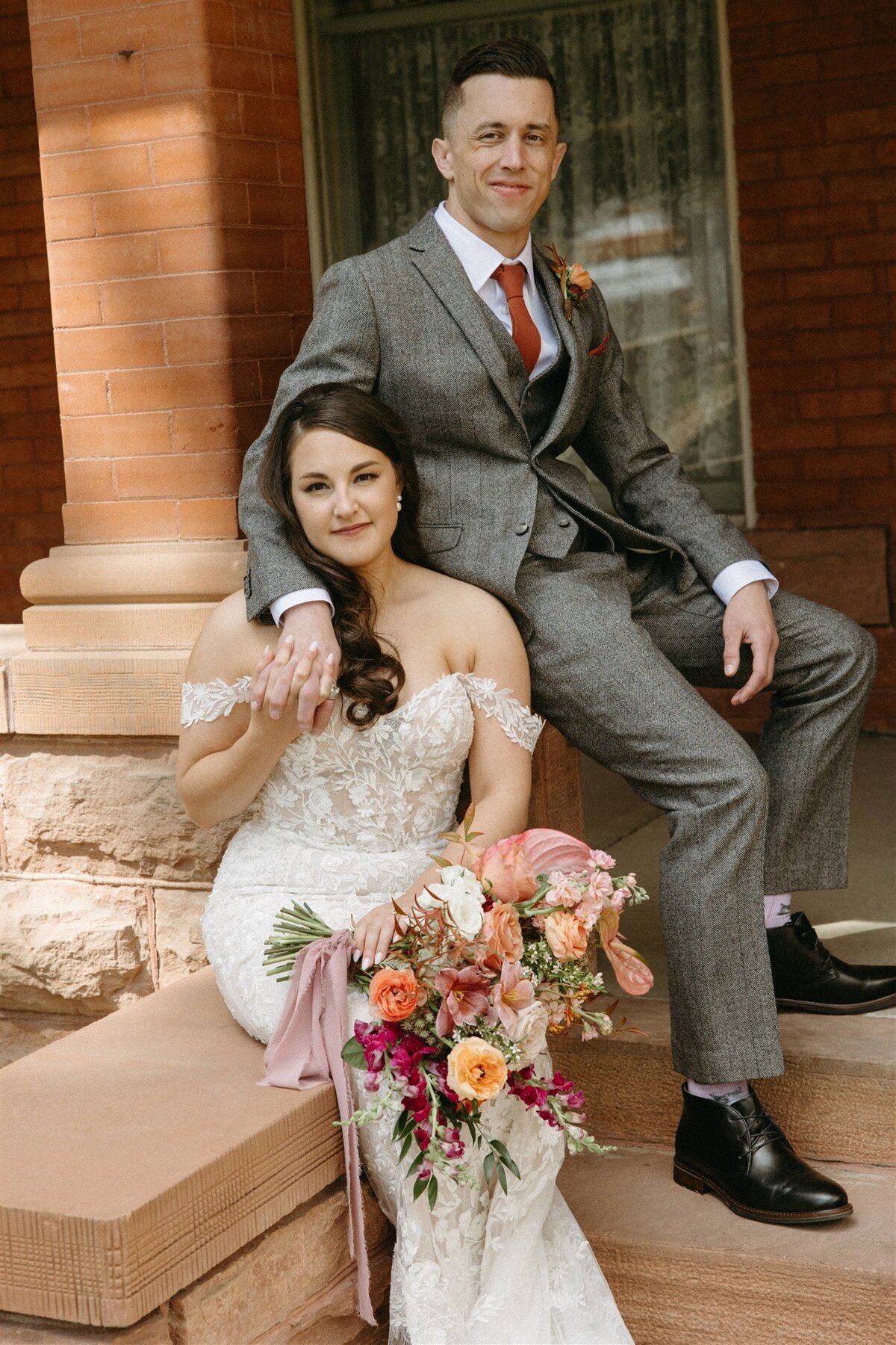 Bride wearing lace dress with groom in grey suit at spring wedding in Longmont Colorado
