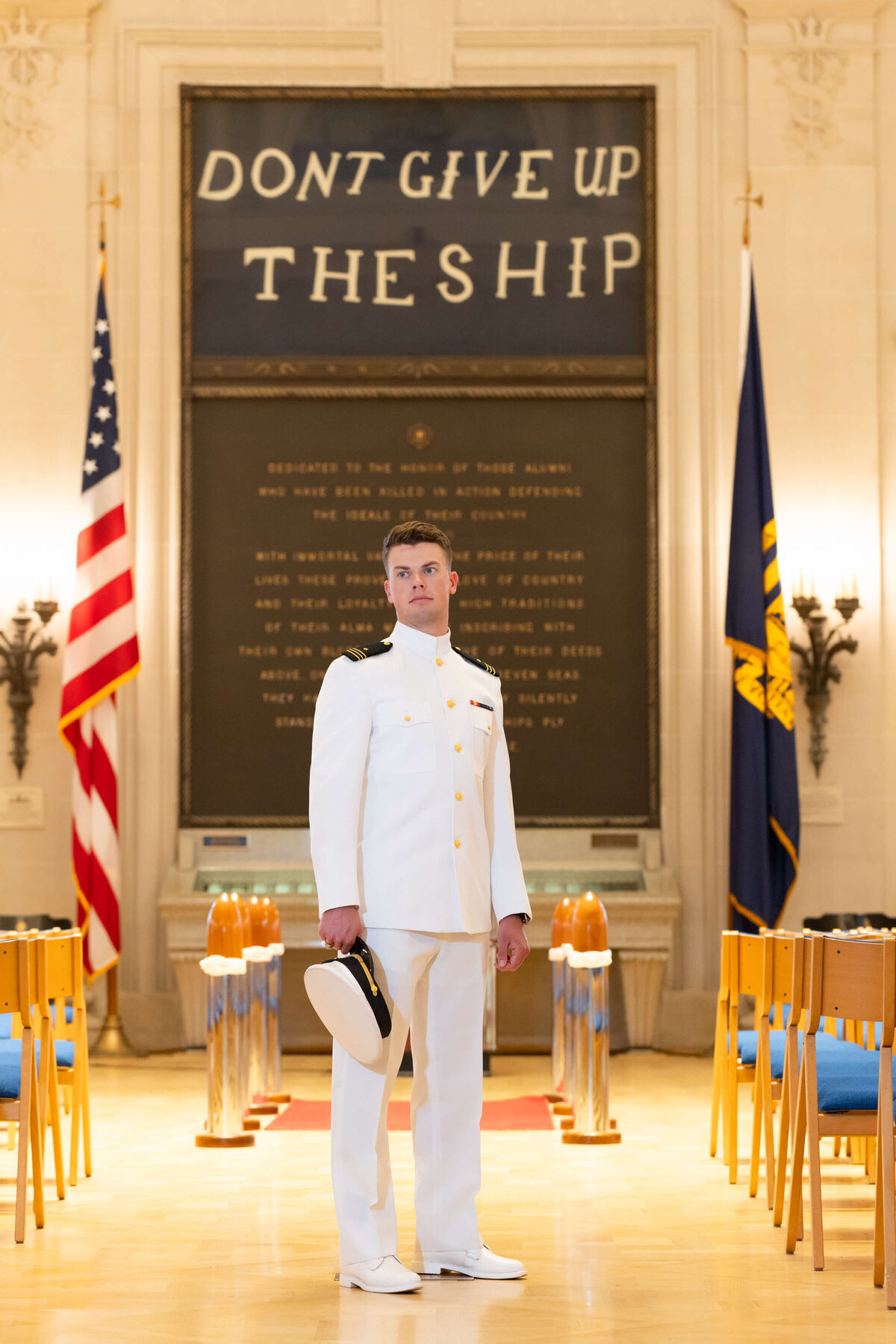 Kelly Eskelsen takes photo of USNA  graduate in white uniform standing in reverence at Memorial Hall at the Naval Academy in Annapolis, Maryland.