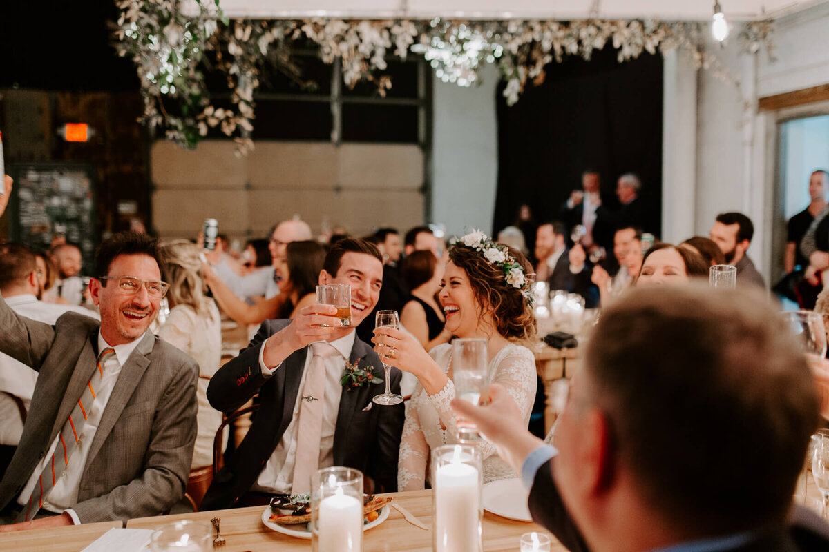 A bride and groom cheers at their wedding reception at O'Maine Studios in Portland, Maine