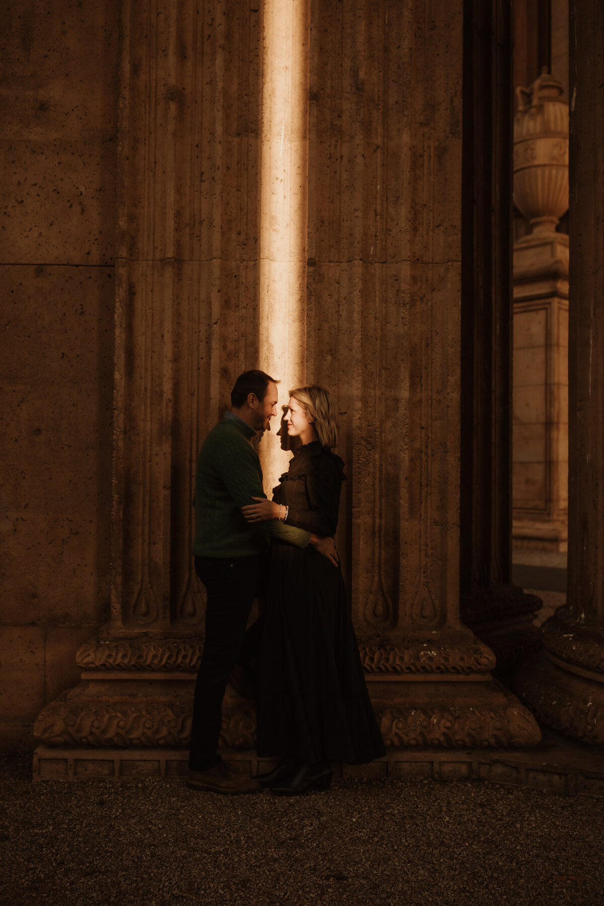 Bay Area couples portrait at Palace of Fine Arts.  Pocket of light illuminates them against Beaux-Arts architecture
