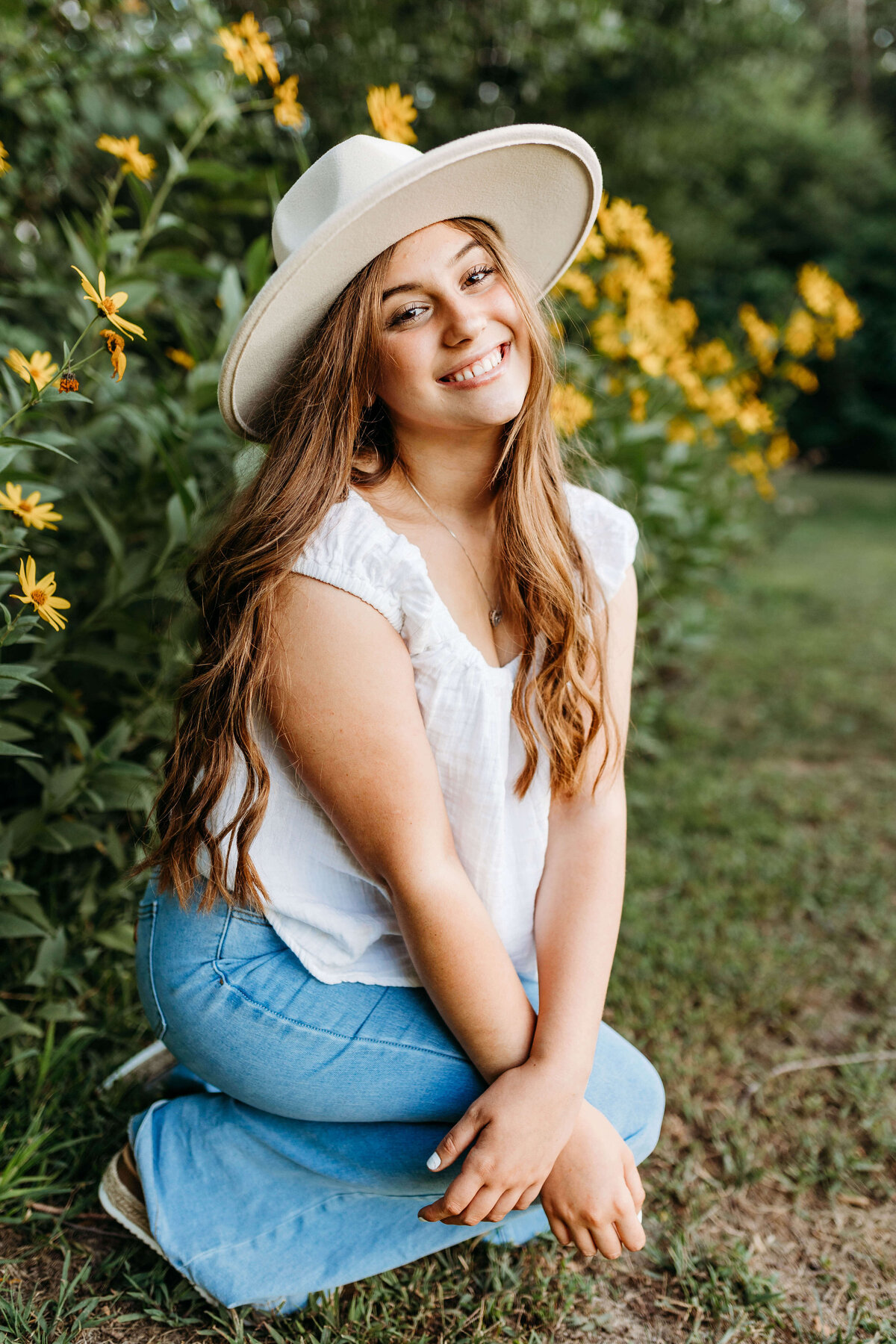 Senior is smiling in front of yellow flowers