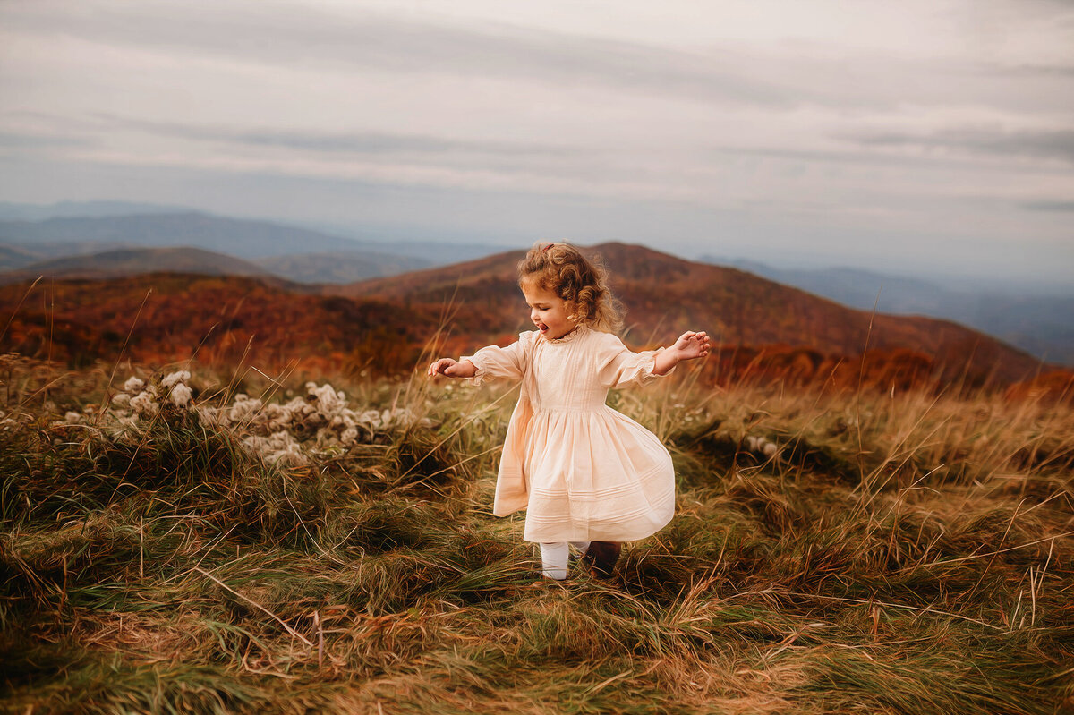 Little girl dances on a mountain top during Family Photoshoot at Max Patch in Asheville, NC.