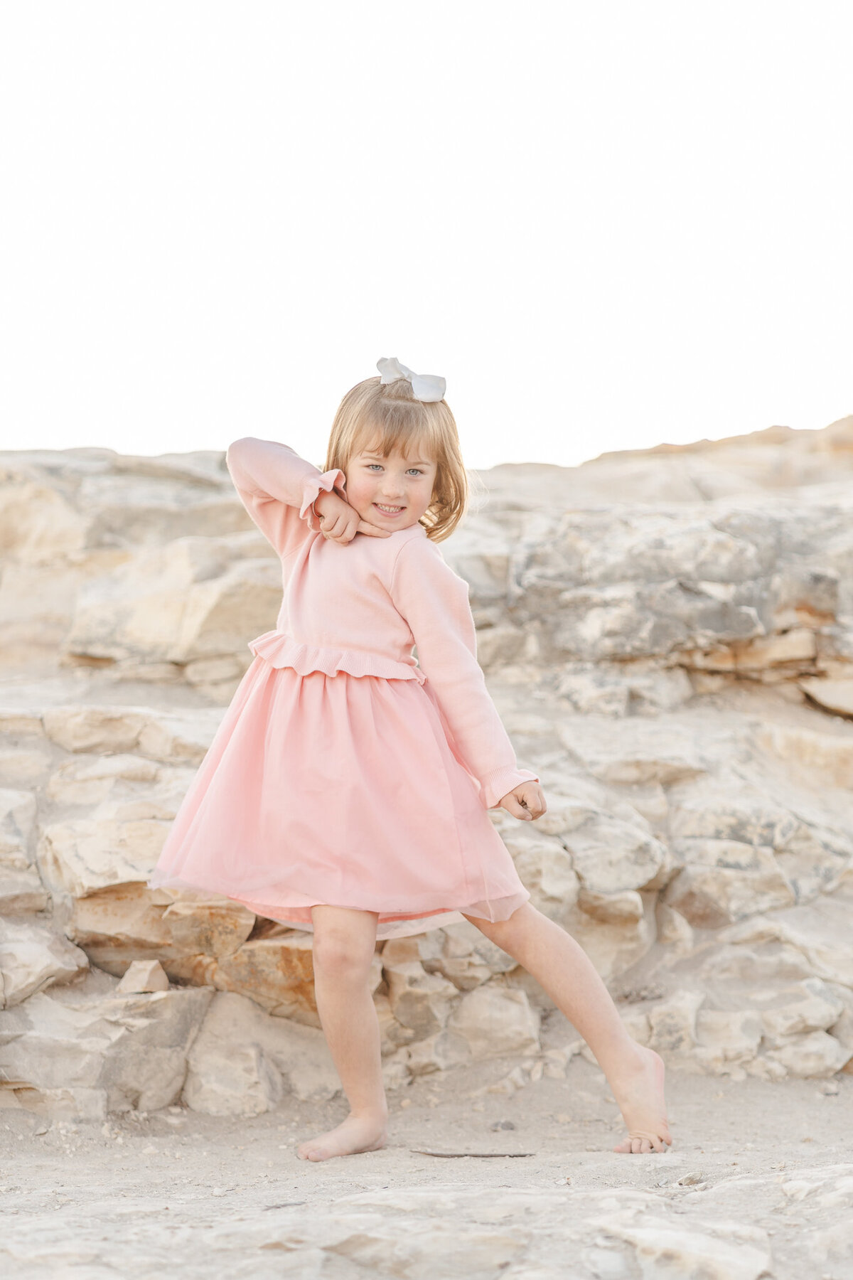 young girl in a pink dress striking a pose for the camera