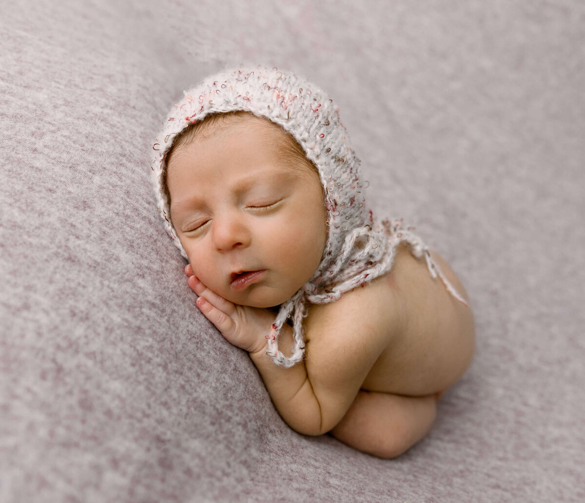 Newborn baby girl wearing a bonnet in an Erie photography studio