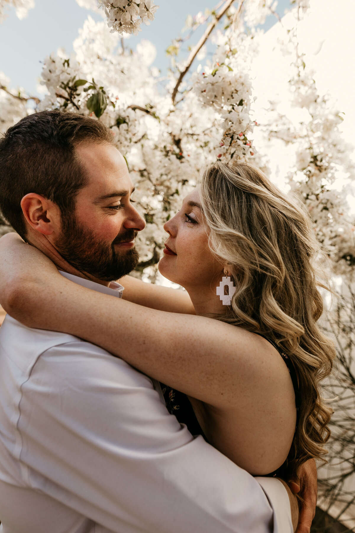 couple about to kiss in from of a tree with white blooms