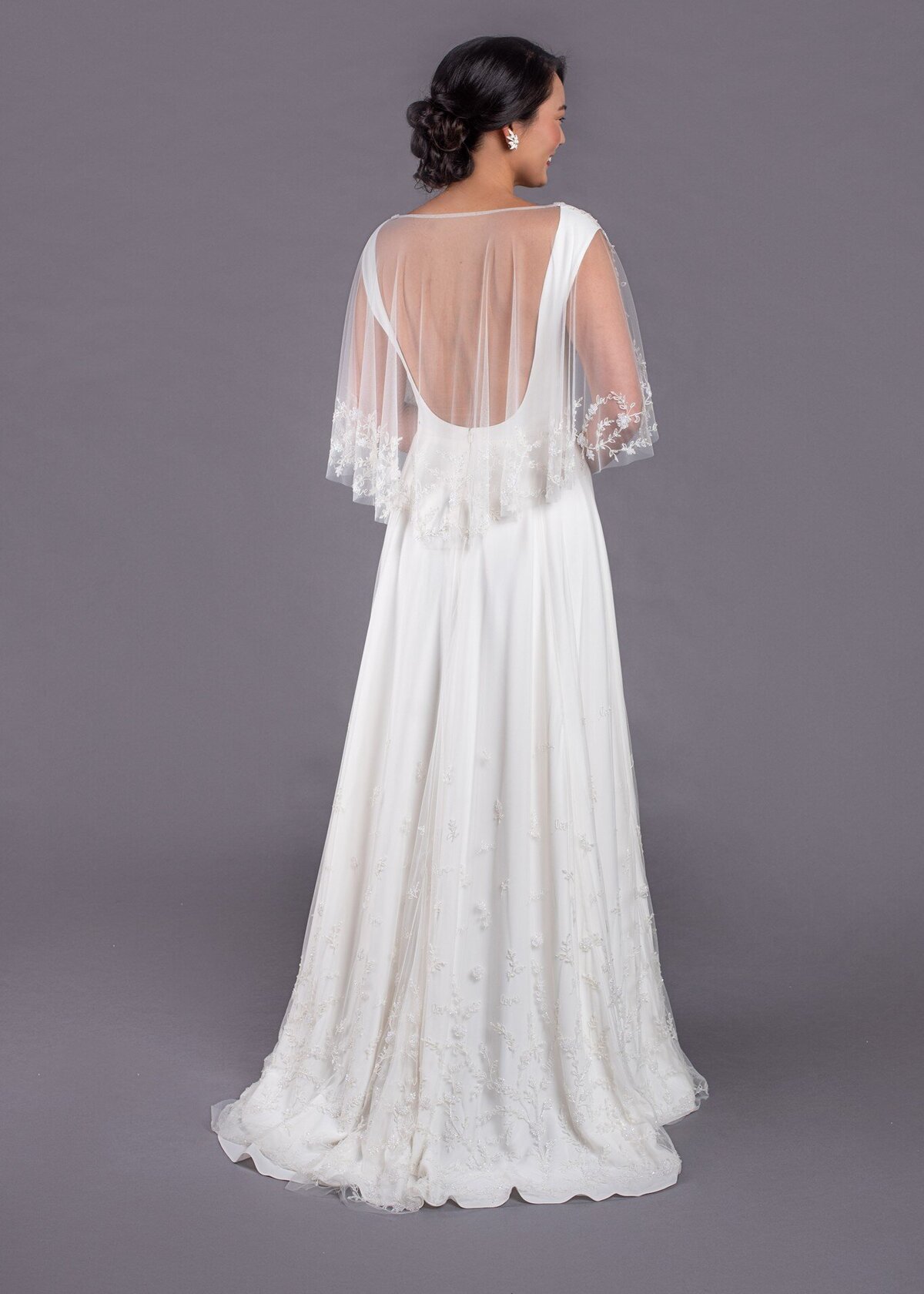The Dolores style by Edith Elan is slim a-line wedding dress with a low back that can be seen through the beaded bridal capelet.