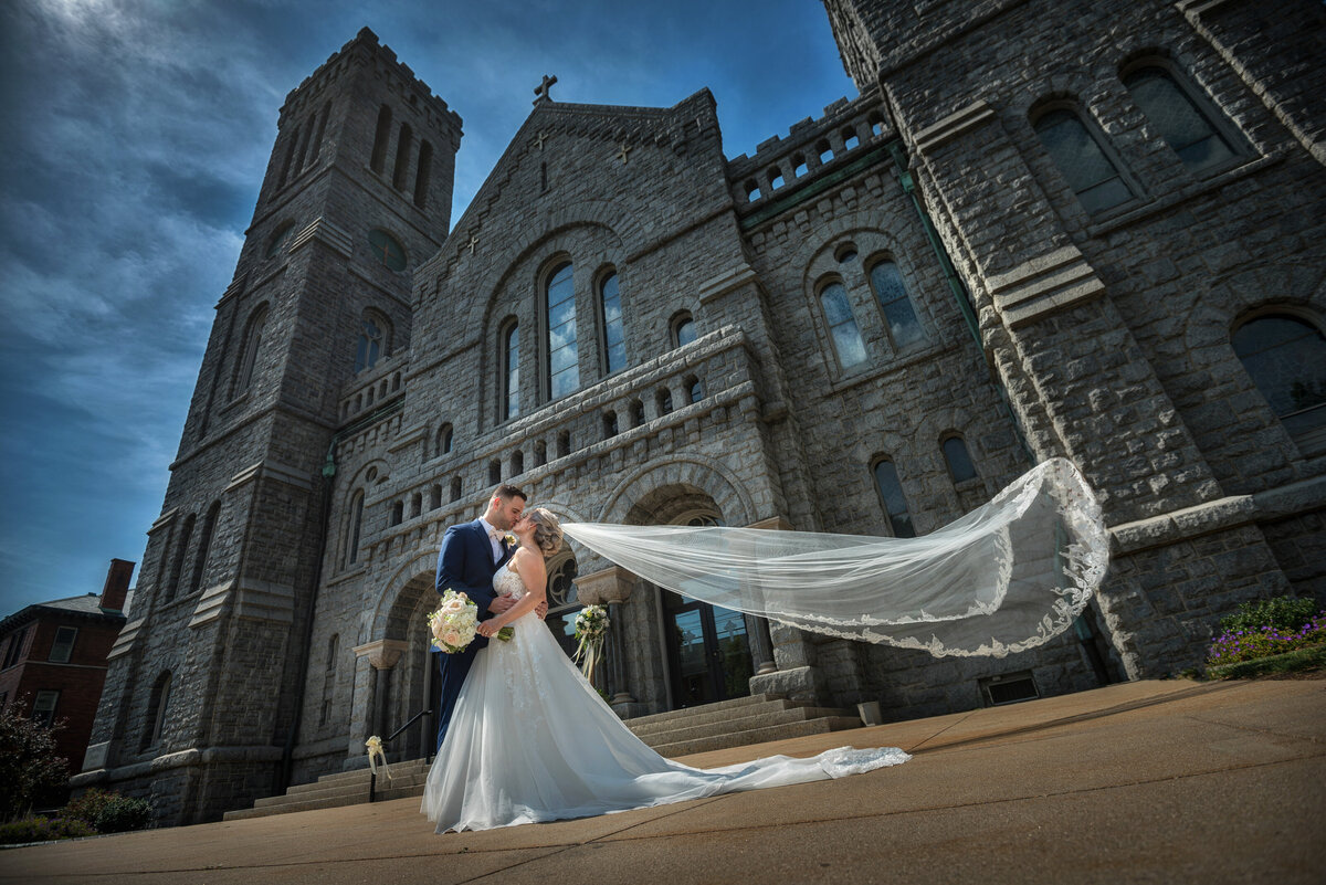 Bride with veil blowing in front of Saint Patrick church in Erie PA.