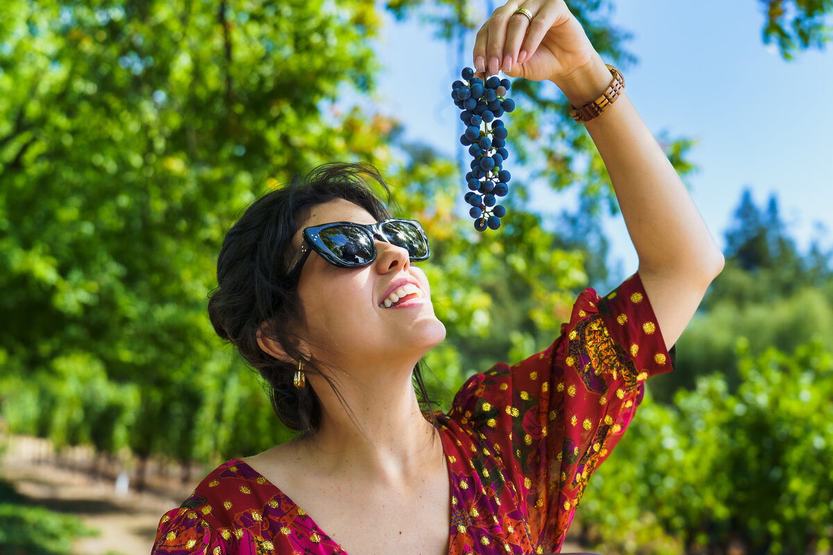 brand photo of a tour guide posing with grapes in a vineyard