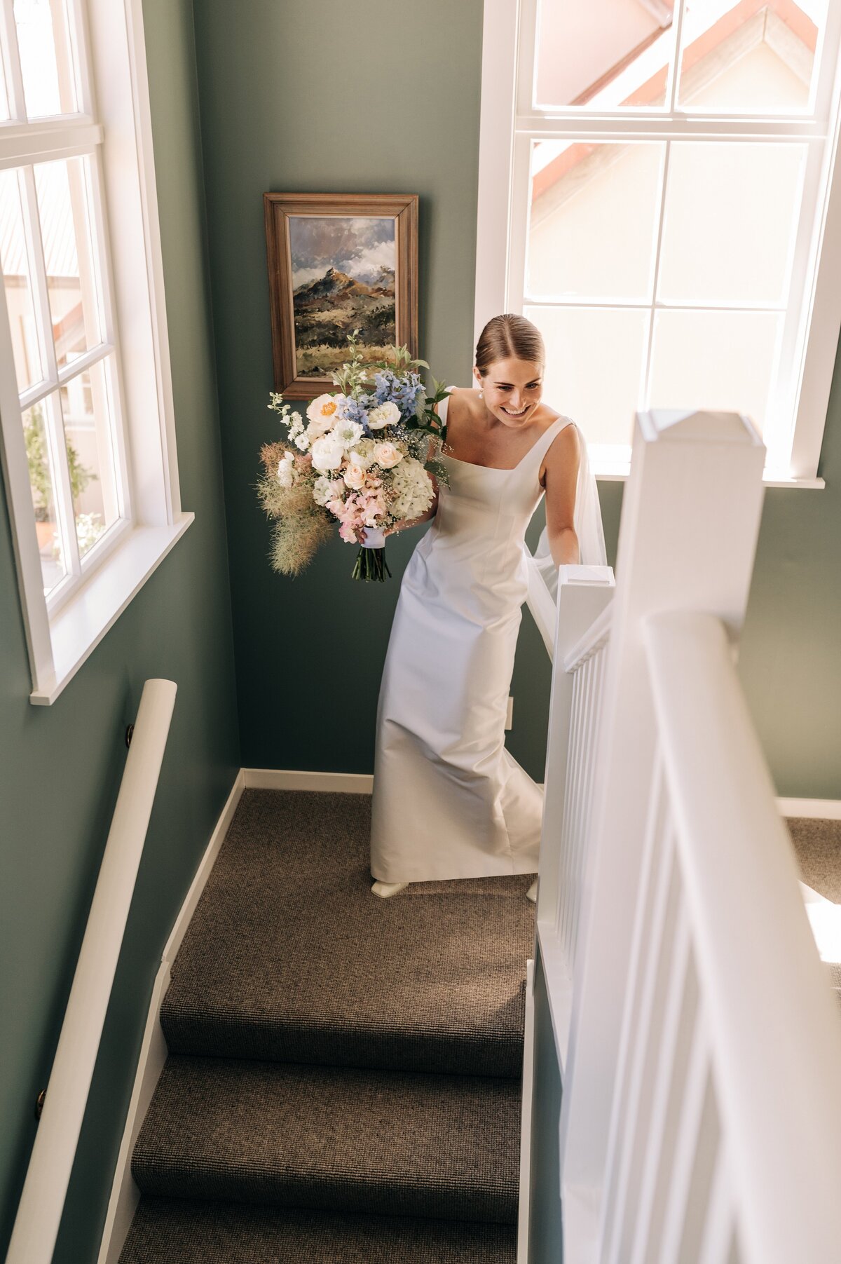 bride in emilia wickstead dress walks down stairs with pastel bouquet and green walls in blenheim nz at her wedding