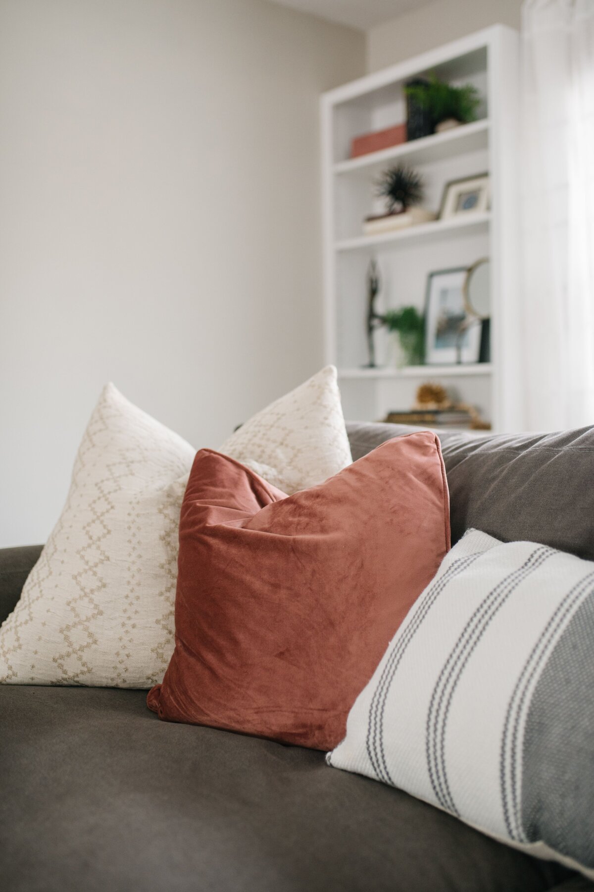 Three textured pillows sits on the corner of a large grey couch