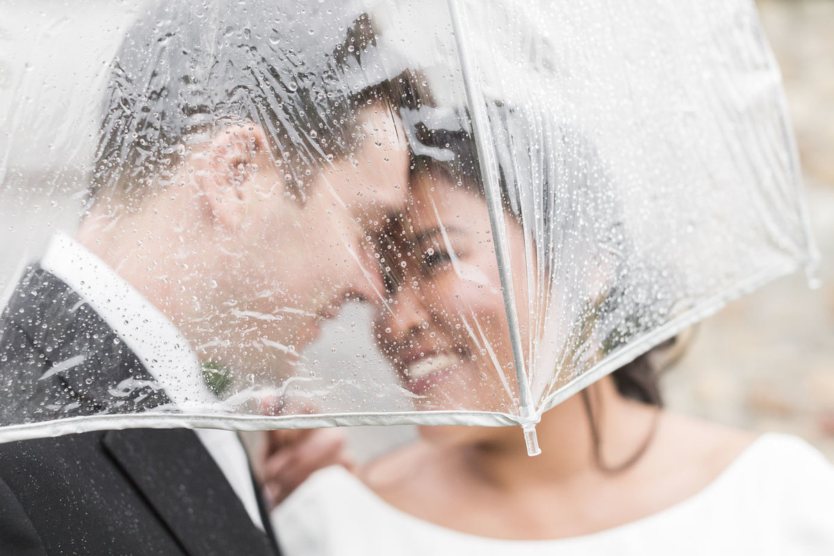 man and woman kissing under umbrella