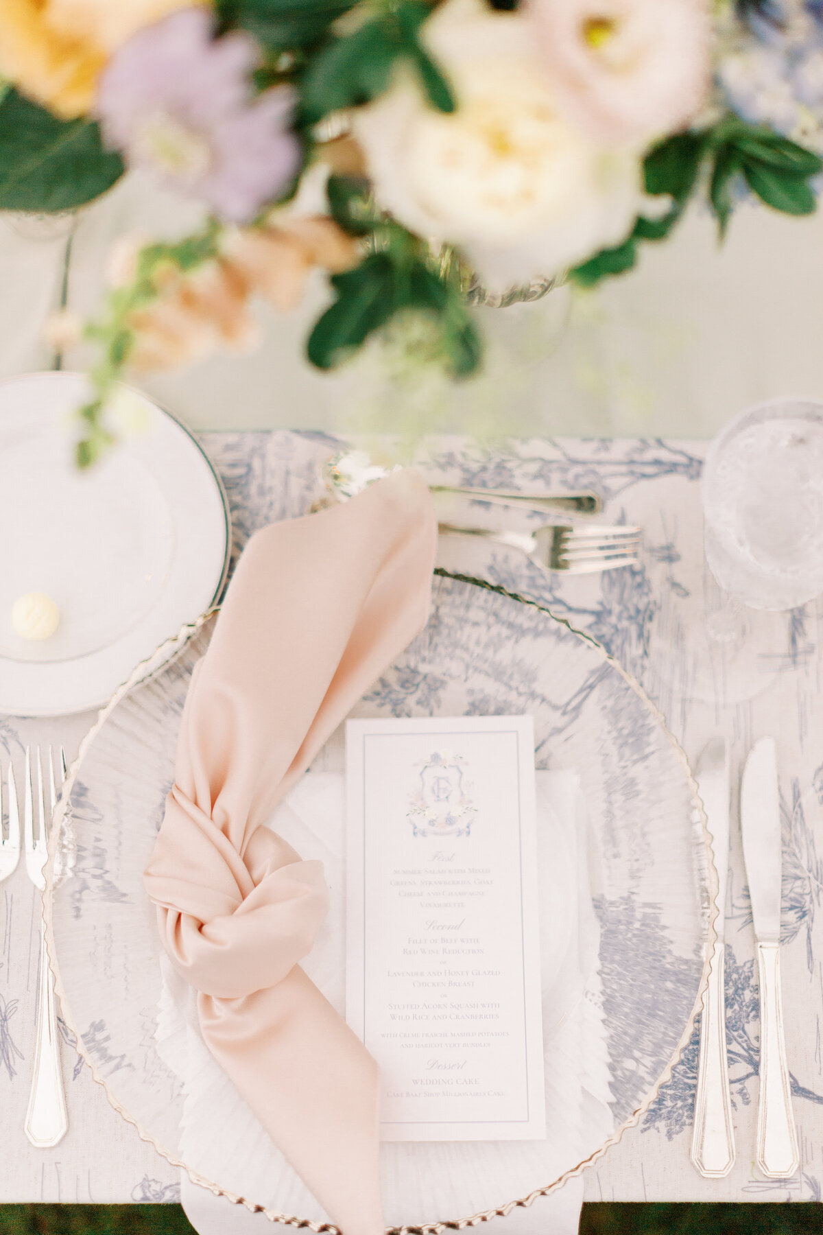 Gold beaded glass charges with a blush linen knot tied napkin for a wedding reception
