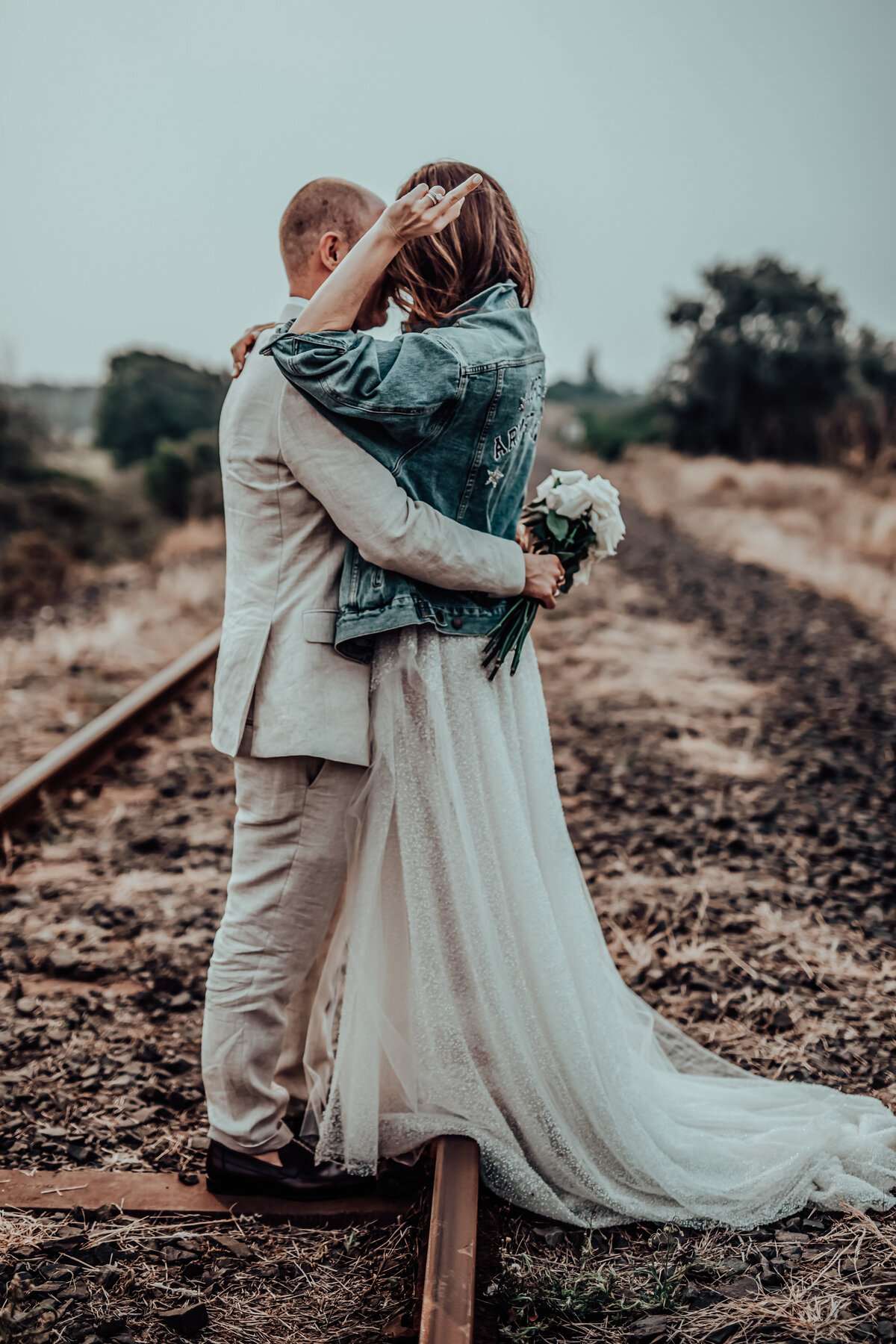Wedded couple posing on railway track with blurred background