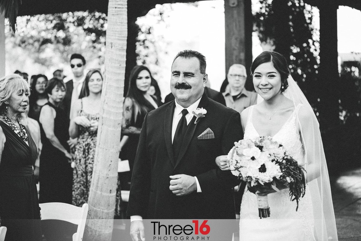 Black and white photo of the Bride being escorted up the aisle by her father