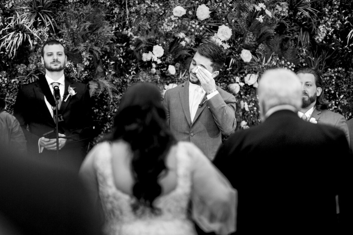 Groom, wiping away a tear as he watches his Bride walk down the aisle during their wedding ceremony at Perona Farms