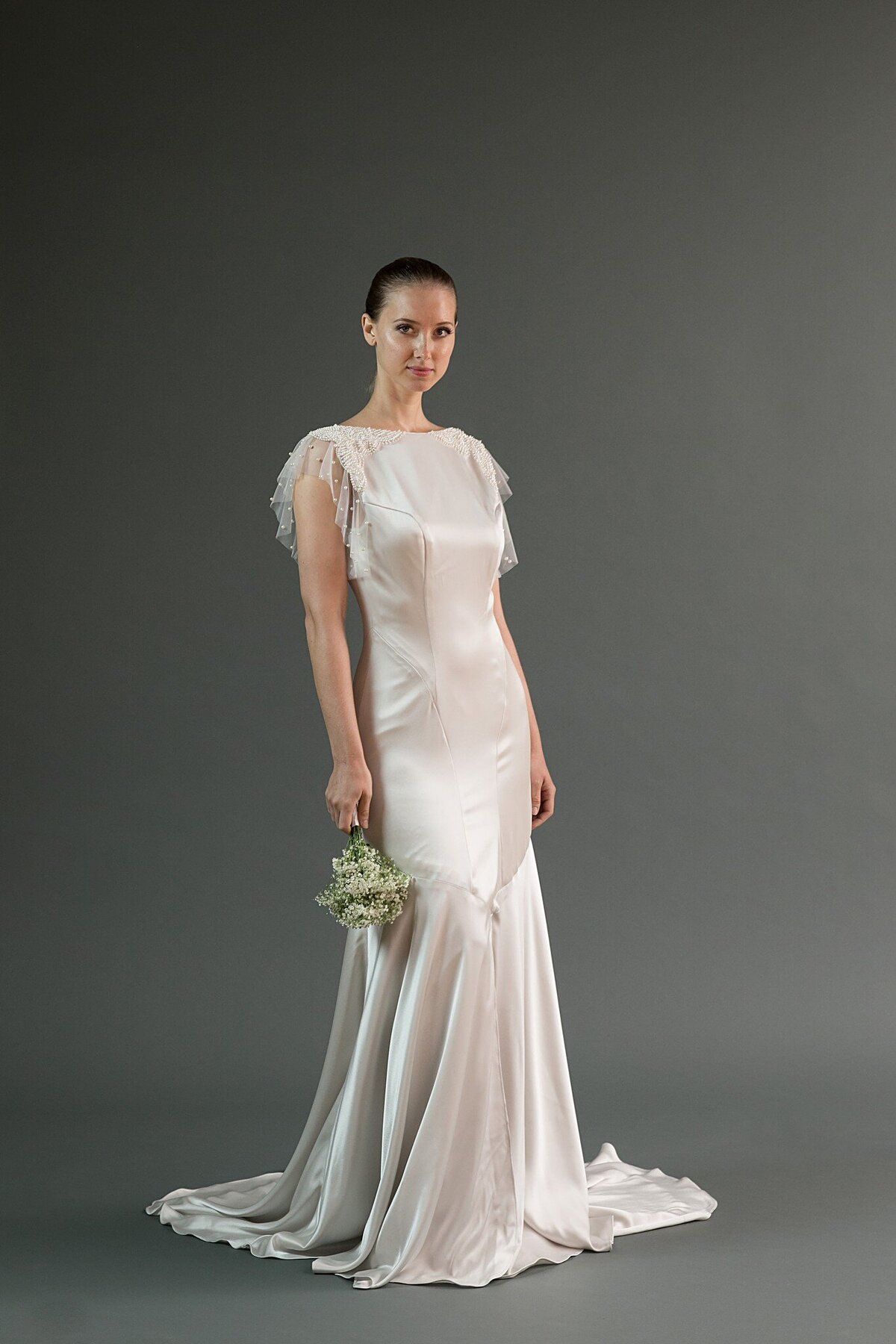 Hana is a high-neck, low-back wedding dress with pearl net flutter sleeves and handmade pearl beading.