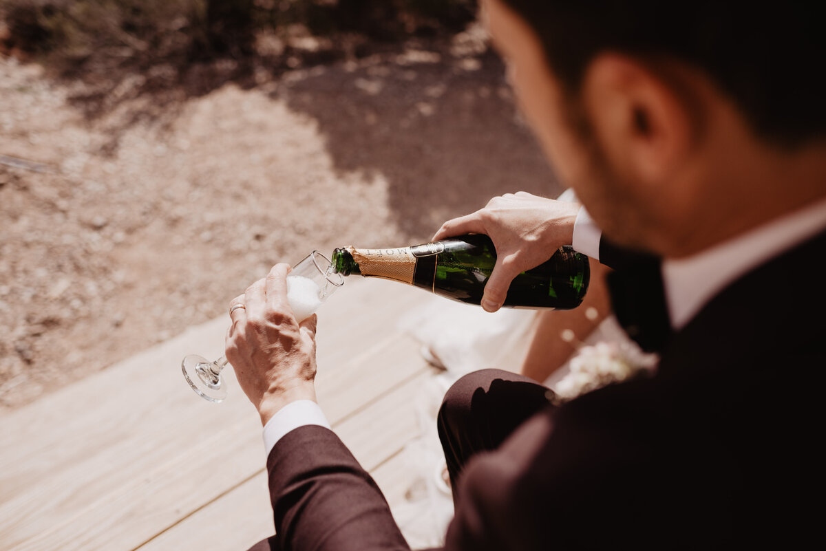Utah elopement photographer captures groom pouring champagne