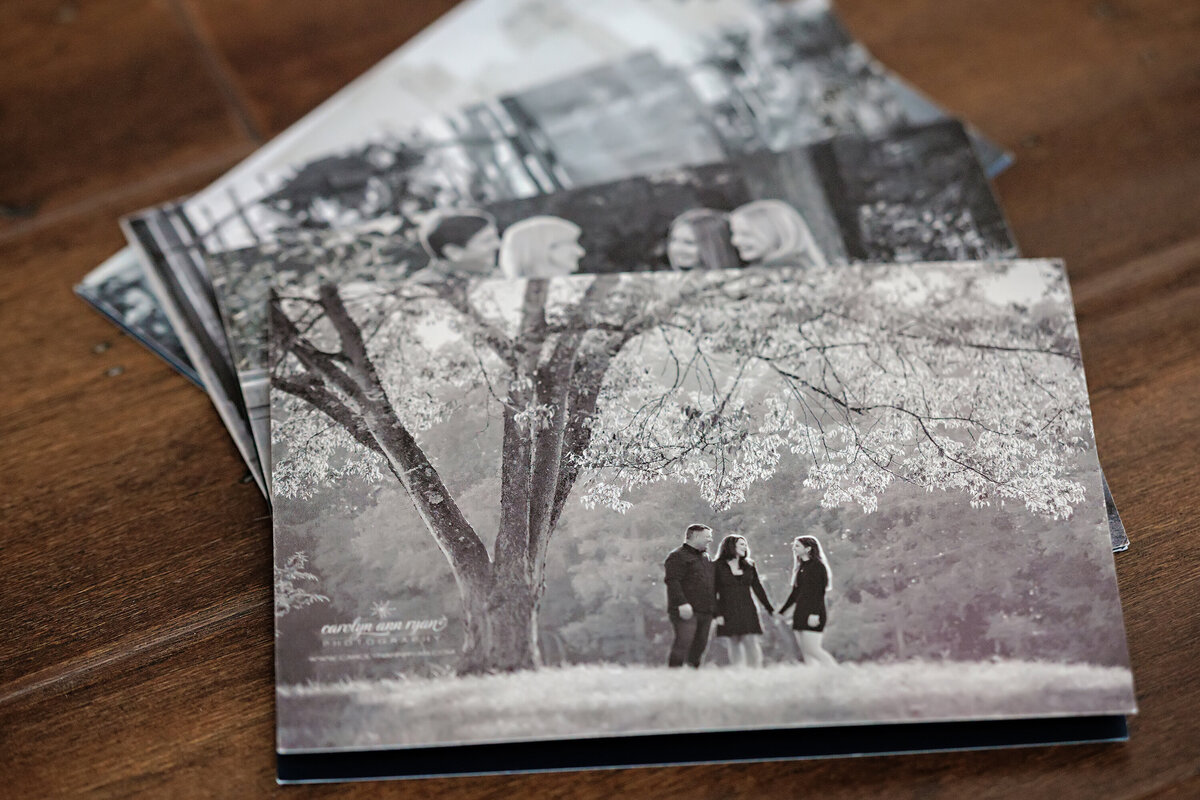 Stack of custom press printed holiday cards on pearl paper featuring signature black and white storytelling images on the back, highlighting the elegant shimmer and personalized design style unique to this collection.