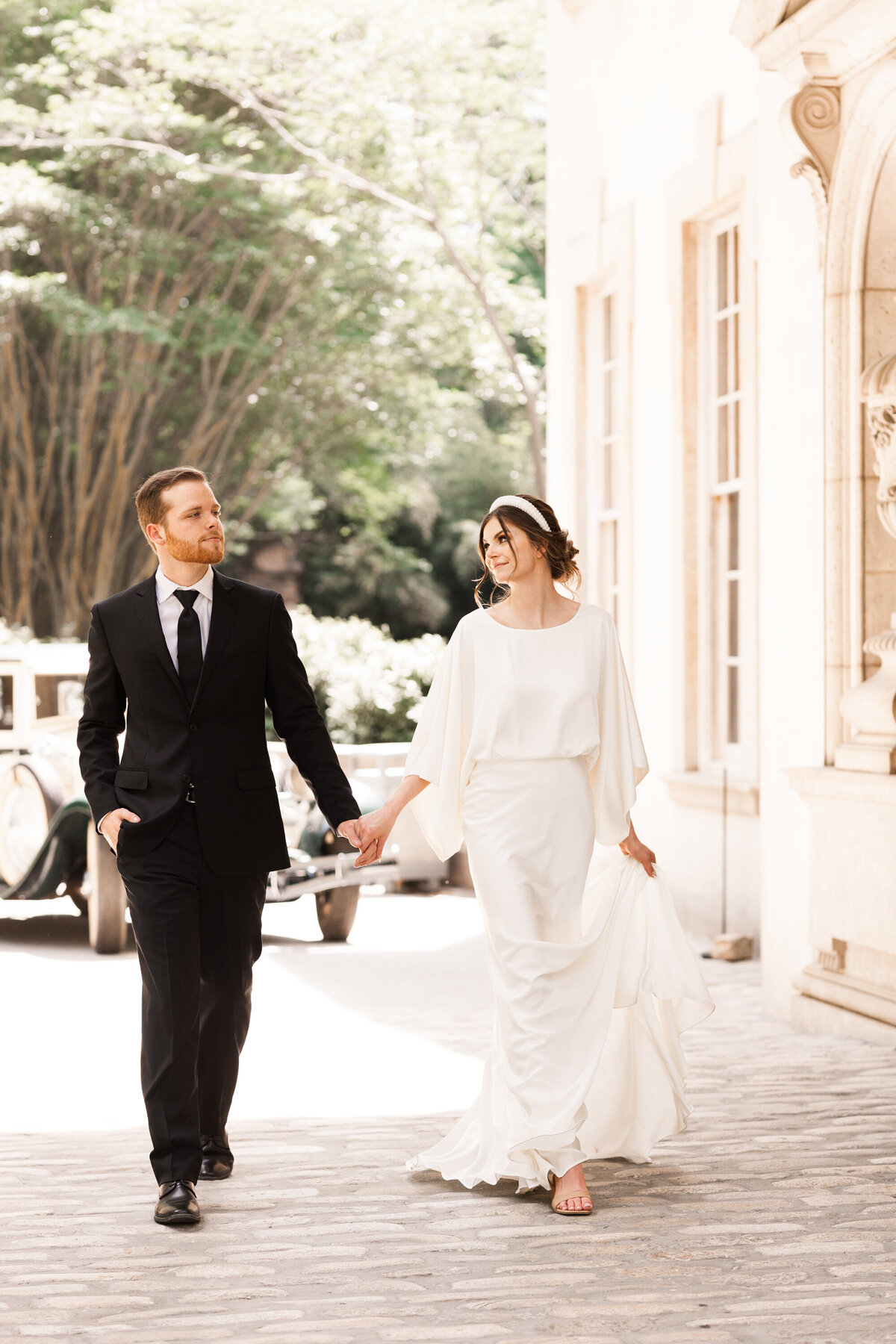 bride and groom walking together in front of a house