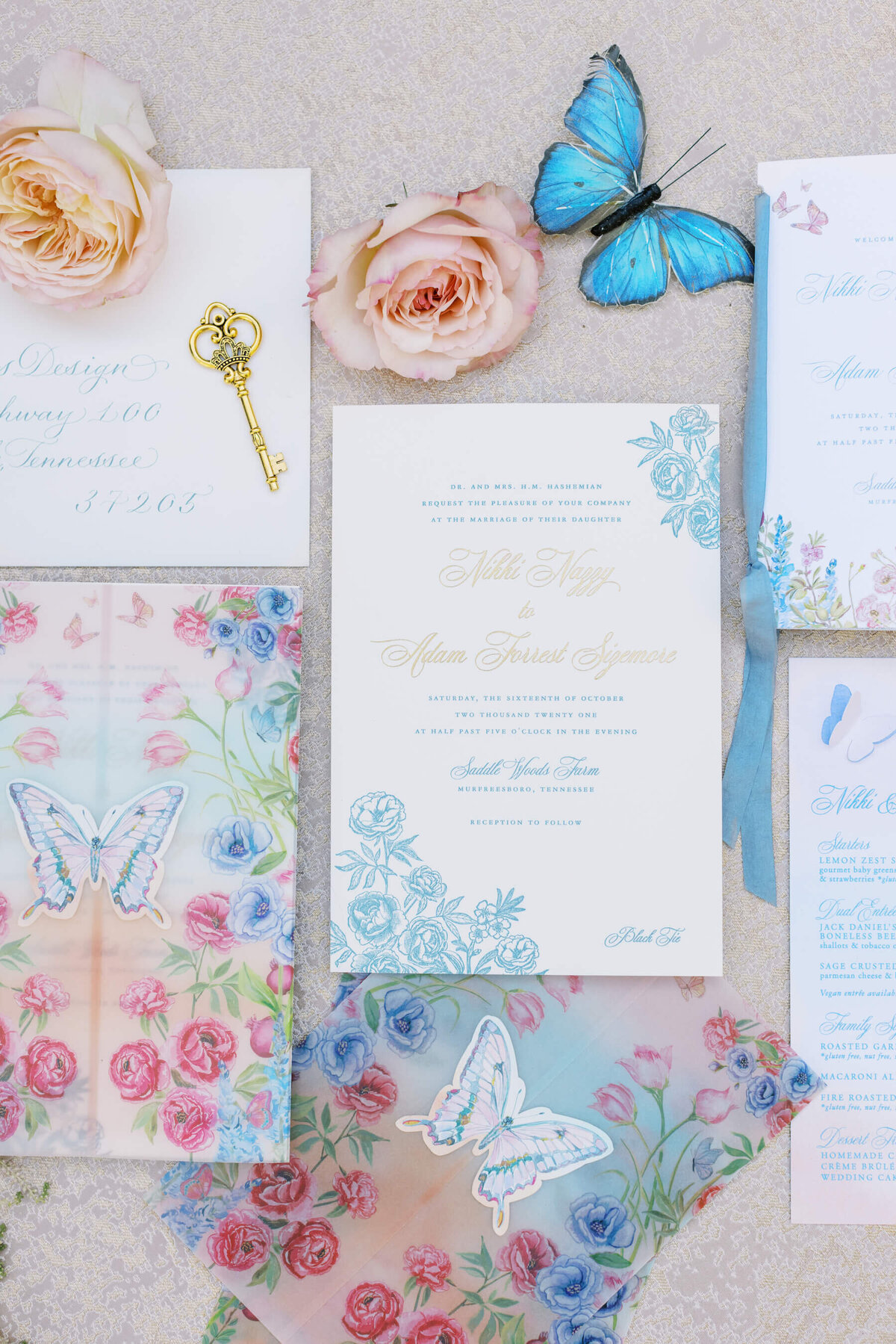 Tenn Hens butterfly and floral wedding invitations with blue ribbon and gold calligraphy.