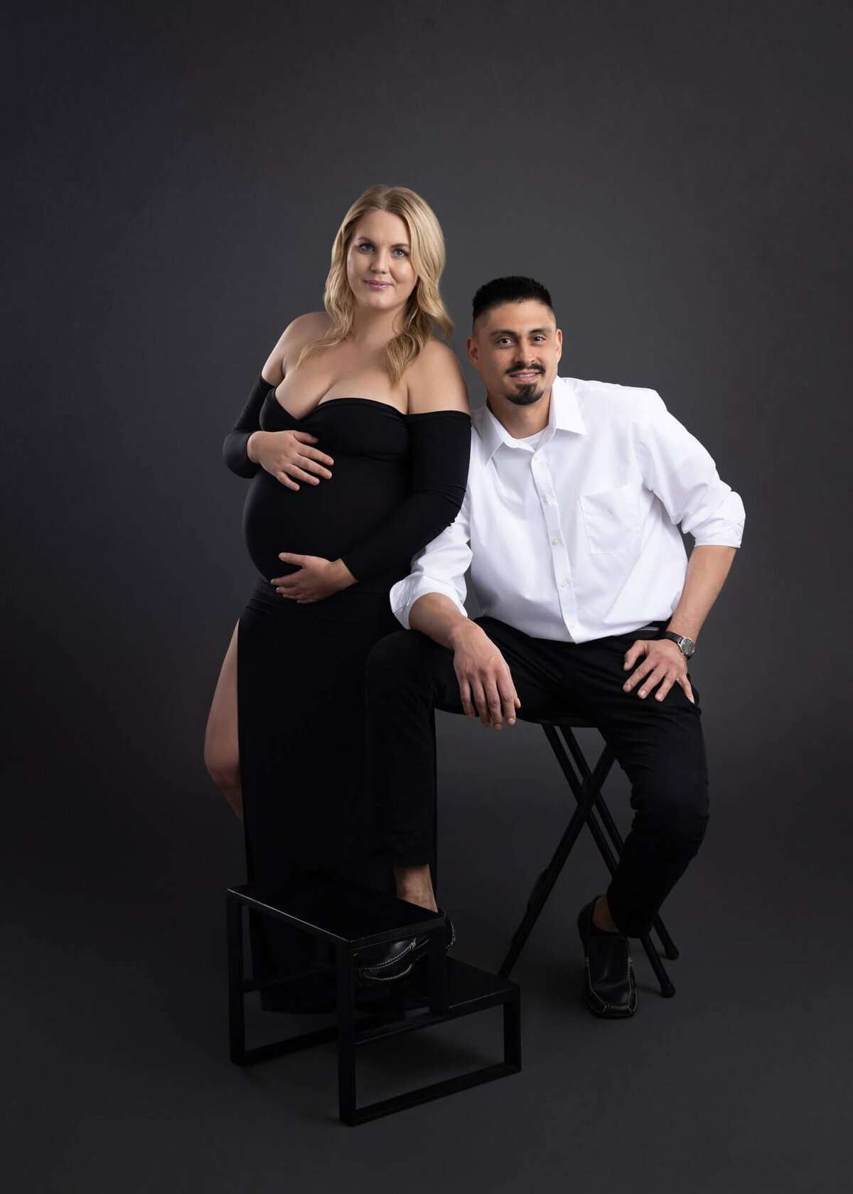 pregnant woman holding her belling standing next to her spouse