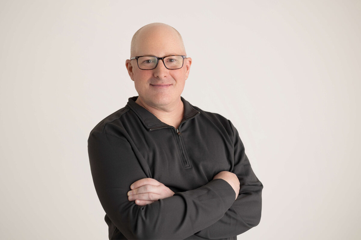 Man in sweater with arms crossed smiling