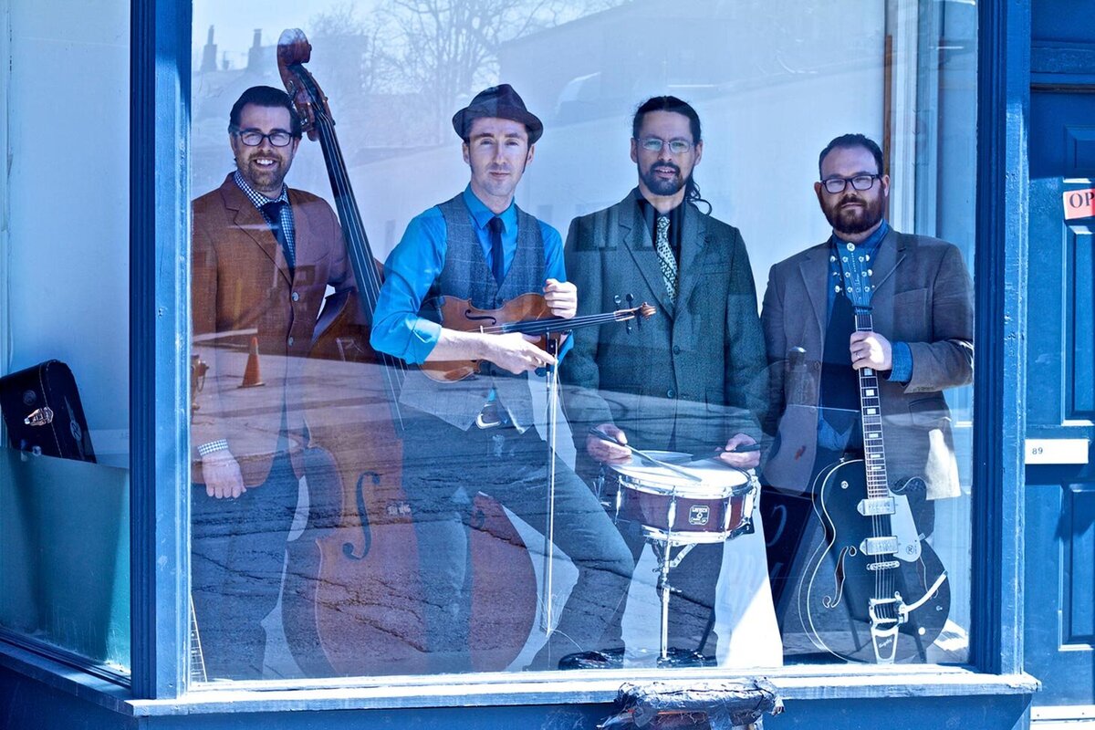 Musical group portrait Gordie MacKeeman And His Rhythm Boys standing with instruments behind reflections  on window