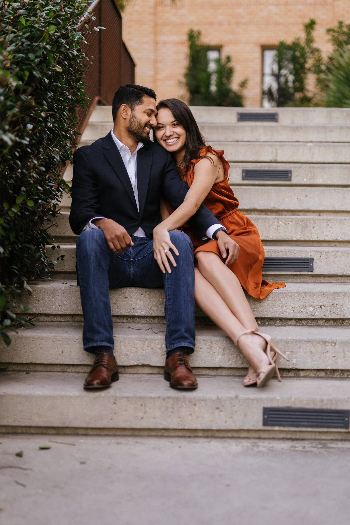 Fiancé staring at his fiancée sitting on steps at the Historic pearl while on their engagement session by Expose The Heart.