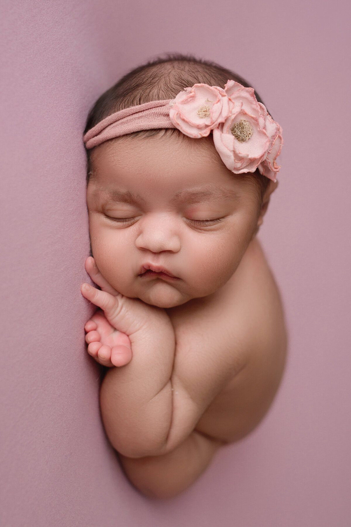 snuggled baby girl sleeping on a pink blanket