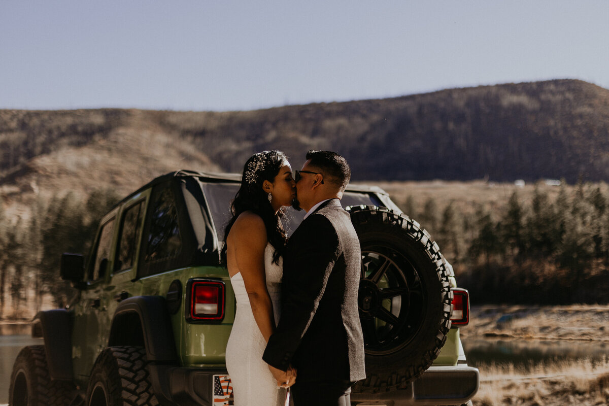 bride adn groom having a first look around the sides of their jeep wrangler