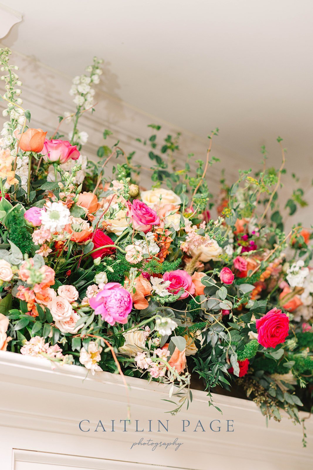 Florals spilling over the fireplace mantle with bright summery blossoms.