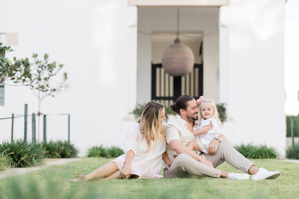 Parents sitting in the grass while one holds a small child