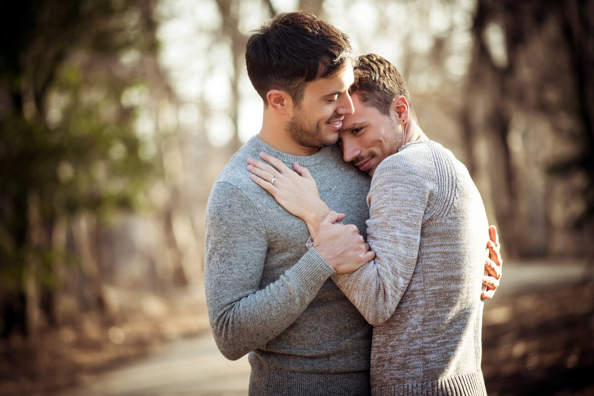 Two men hugging while standing in a wooded area.
