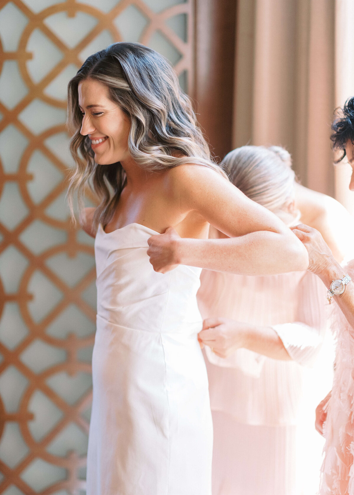 Virginia Wedding Photographer takes an image of the Maid of Honor and Mother help brunette bride into her dress